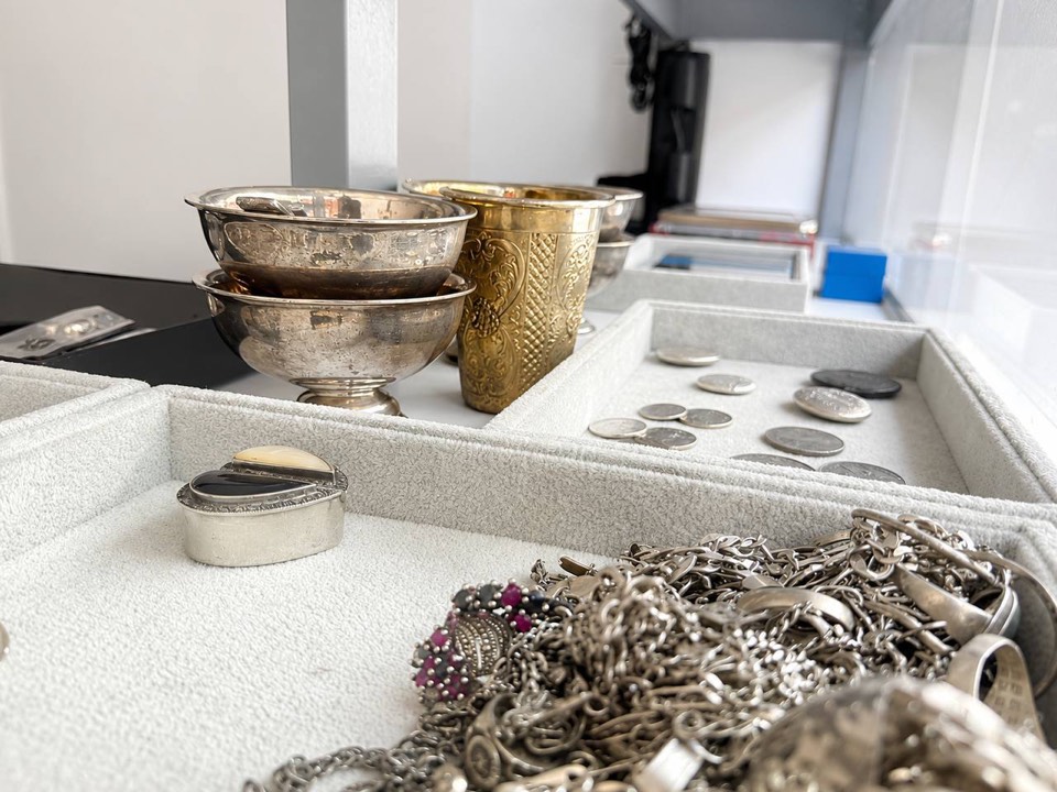 Silver bowls, coins, and jewelry in a display case